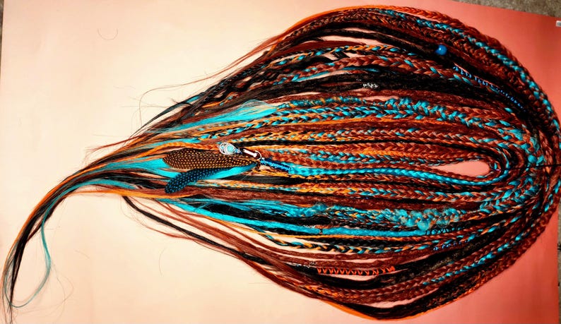 May include: A collection of long, synthetic, crocheted dreadlocks in brown, orange, black, and turquoise colors. The dreadlocks are whispy ended so length is customisable, they have beads and other decorative elements woven into them.