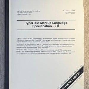 Pode incluir: Um documento impresso intitulado "HyperText Markup Language Specification - 2.0" de 1994. A capa é branca com texto preto e uma lombada preta. O documento é um rascunho da Internet da Internet Engineering Task Force.