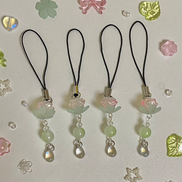 May include: Four green and pink flower charms with clear beads and a teardrop-shaped crystal hanging from a black string.