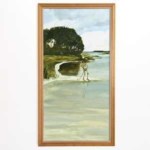 May include: A framed painting depicts a skeleton figure walking on water near a shoreline. The artwork features a muted color palette with shades of green, blue, and brown. A large tree and cloudy sky are in the background. The frame is a light brown color.
