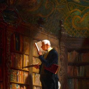 May include: A man in a dark suit and white shirt stands in a library, reading a book. He is surrounded by bookshelves filled with books. The library has a high ceiling with ornate details.