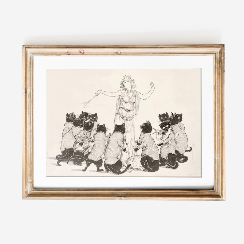May include: A framed black and white illustration depicts a woman in a flowing gown with a crown, holding a wand, surrounded by cats. The cats are wearing sweaters and appear to be in a circle, with a light-colored background.