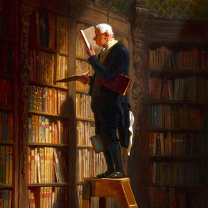 May include: A man in a dark suit and white cravat stands on a wooden stepladder in a library, reaching for a book on a high shelf. The library is filled with bookshelves, all lined with books.