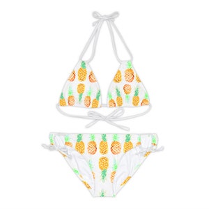 May include: White bikini with a pineapple print. The top is a triangle style with adjustable straps and ties at the back. The bottom is a high-cut style with ties on the sides.