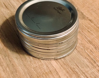 May include: A stack of silver metal canning lids with the text "Ball SureTight" on the top lid.