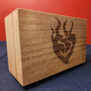 May include: A wooden box with a dark brown stain. The box has a stylized flame design carved into the front.