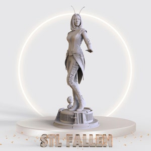 May include: A white 3D printed figurine of a female superhero with insect-like antennae, standing on a platform with a smaller figurine. The platform has a textured surface and the text "STL FALLEN" is printed on the base.