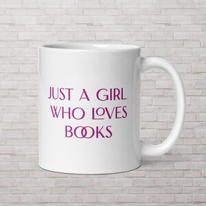 May include: White ceramic mug with a purple inscription that reads "Just a girl who loves books" with two stylized purple rings in place of the "O" in books.