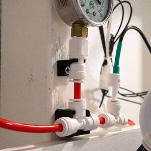 May include: A white pressure gauge with a black needle and a red and white pipe system. The gauge reads up to 100 PSI and has a black and white label that says "PSI BAR 100000 PSI".