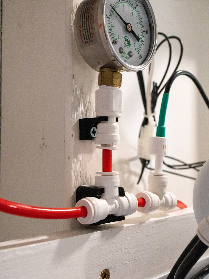 May include: A white pressure gauge with a black needle and a red and white pipe system. The gauge reads up to 100 PSI and has a black and white label that says "PSI BAR 100000 PSI".