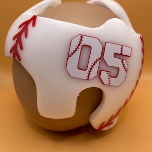 May include: White foam helmet with red baseball stitching and the number 05 in red with a white baseball stitch design.