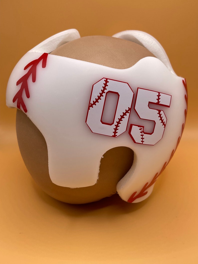May include: White foam helmet with red baseball stitching and the number 05 in red with a white baseball stitch design.