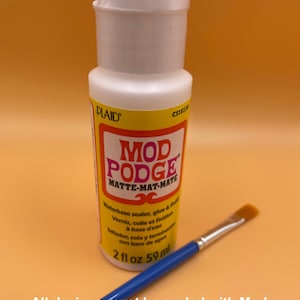 May include: A white bottle of Mod Podge Matte-Mat-Mate sealant with a blue brush. The bottle label says "Waterbase sealer, glue & finish" and "2 fl oz 59 ml".