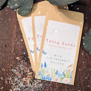 May include: Three small, beige envelopes with a floral design and the text "Fairy Seeds Pacific Coastal Mix with Eco-Friendly Glitter" printed on the front.
