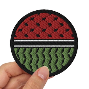 May include: A round, black-bordered patch with a red and green design. The top half of the patch is red with a white stripe, and the bottom half is green.