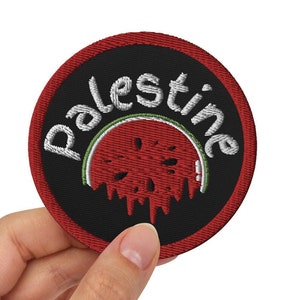 May include: A black and red embroidered patch with the word "Palestine" in white lettering and a red watermelon graphic.