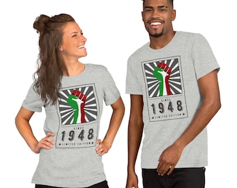 May include: Gray t-shirt with a graphic of a raised fist with red, green, and white colors. The graphic is surrounded by a sunburst design and the text "Since 1948 Limited Edition".