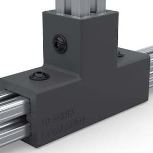 May include: Close-up of a dark gray T-shaped connector with black screws, attached to two parallel silver metal rails. The text "10-SERIES COMPATIBLE" is visible on the connector. The background is white.