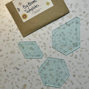 May include: Three clear plastic quilting templates for making large flower blocks. The templates are labelled "Broken River Quilts" and "Big Blooms".