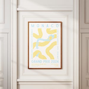 Może przedstawiać: Plakat z ż&oacute;łto-niebieską ilustracją toru wyścigowego Grand Prix Monako. Na plakacie widnieje napis "MONACO" u g&oacute;ry i "GRAND PRIX 2024" na dole.