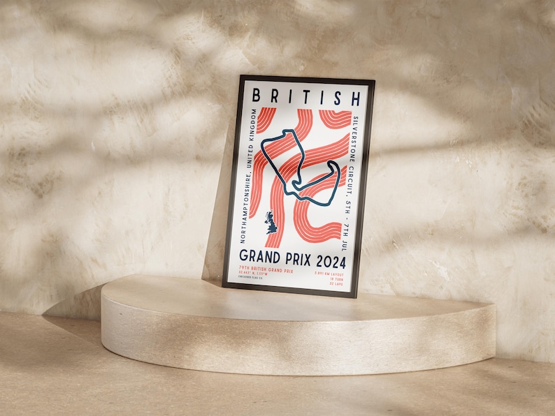 May include: A poster with a black frame advertising the British Grand Prix 2024. The poster features a stylized map of the Silverstone Circuit in red and blue on a white background. The text on the poster reads "BRITISH GRAND PRIX 2024" and "SILVERSTONE CIRCUIT, STH - 7TH JUL".