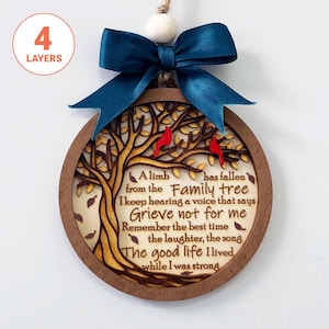 Könnte beinhalten: Runder Holzschmuck mit Baumdesign, zwei roten Vögeln und blauem Band. Der Text lautet: "Ein Ast ist vom Familienbaum gefallen... Trauert nicht um mich... Das gute Leben, das ich lebte".