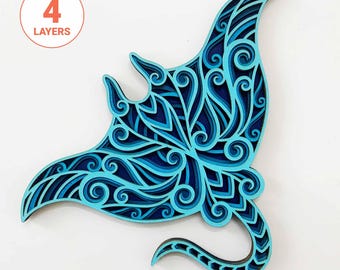 May include: A blue and teal layered papercut of a manta ray with intricate swirling patterns. The papercut is made of four layers and is a decorative wall art piece.
