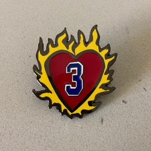 May include: A red heart with a blue number 3 inside, surrounded by yellow flames. The heart and flames are outlined in black.
