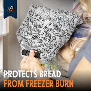 May include: A white reusable bread bag with a black and white pattern of various bread types. The bag is being held by a hand and the text "PROTECTS BREAD FROM FREEZER BURN" is printed in orange on a white background.