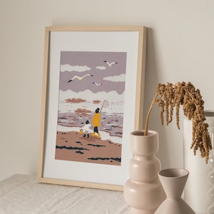 Op de afbeelding: Een ingelijste illustratie van twee mensen die met een net over het strand lopen. De lucht is paars met witte wolken en er vliegen zeemeeuwen over. De mensen dragen gele regenjassen en het strand is bruin met golven.
