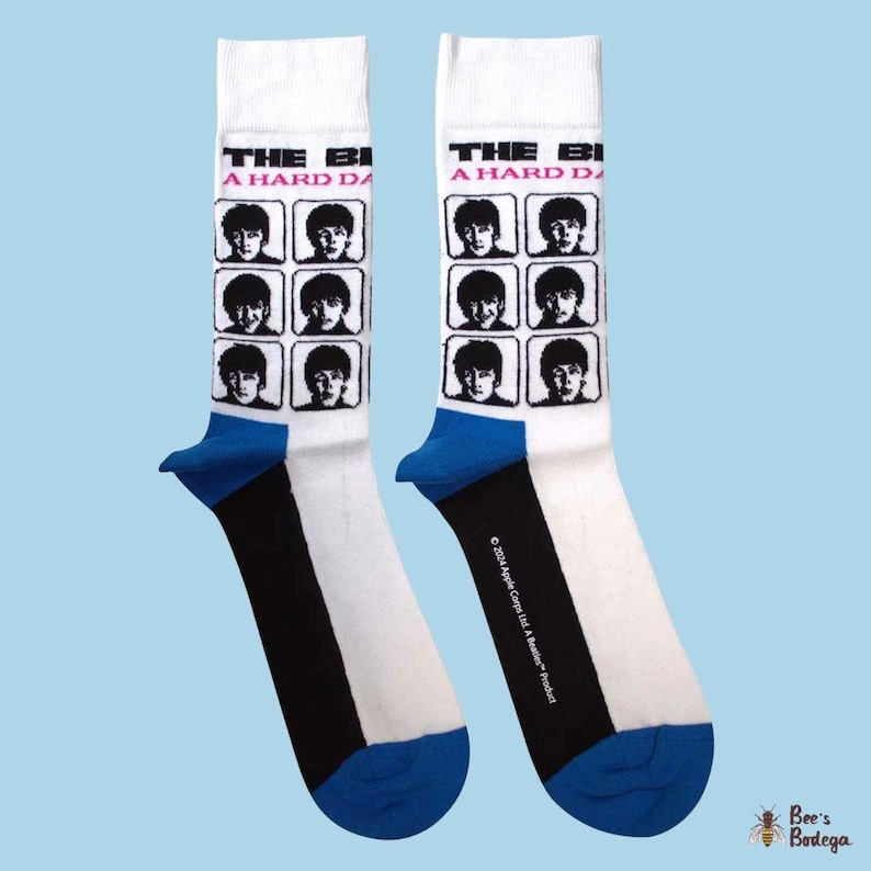 Op de afbeelding: Paar witte sokken met een blauwe hiel en teen, en een zwarte streep. De sokken hebben een raster van zwart-wit afbeeldingen van The Beatles en de tekst "THE BEATLES A HARD DAY'S NIGHT".