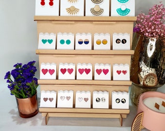 May include: Wooden display stand featuring a selection of colourful earrings. The earrings are arranged in rows on the stand, with various styles including hearts, circles and fans. The stand is labelled "OAK CRAFT & CO."