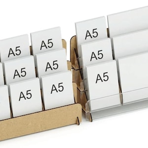 May include: Two tiered display stands for A5 paper. One stand is constructed from light brown wood with three rows of slots, while the other is made of clear acrylic with three tiers. Both organisers hold multiple white A5 labelled cards.