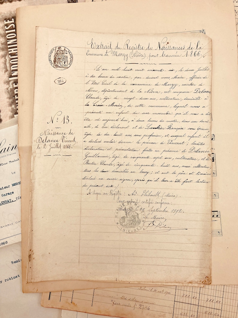 May include: A close-up of a handwritten document in French, dated 1866, with a seal of the city of Nievre. The document is titled "Extrait du Registre des Naissances de la Commune de Marzy (Ni&egrave;vre), pour l'ann&eacute;e 1866." The document records the birth of a child named Delance Vincent, born on July 2, 1866.