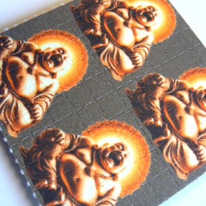 May include: A sheet of brown paper with four images of a laughing Buddha printed on it. Each Buddha is surrounded by a halo of orange light.