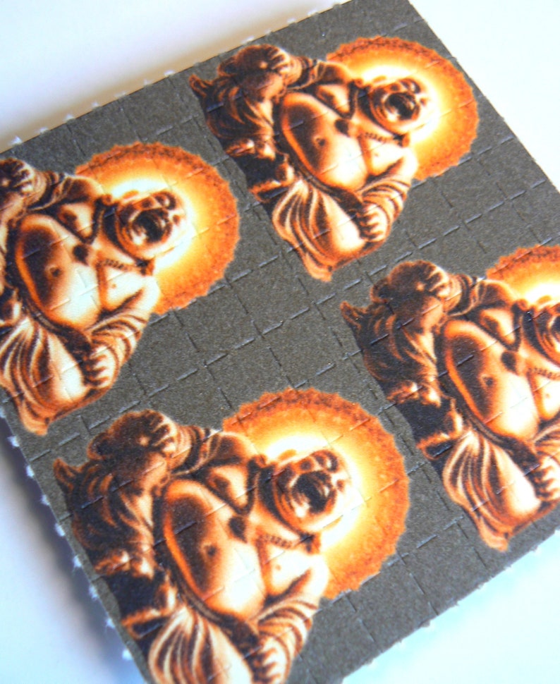 May include: A sheet of brown paper with four images of a laughing Buddha printed on it. Each Buddha is surrounded by a halo of orange light.