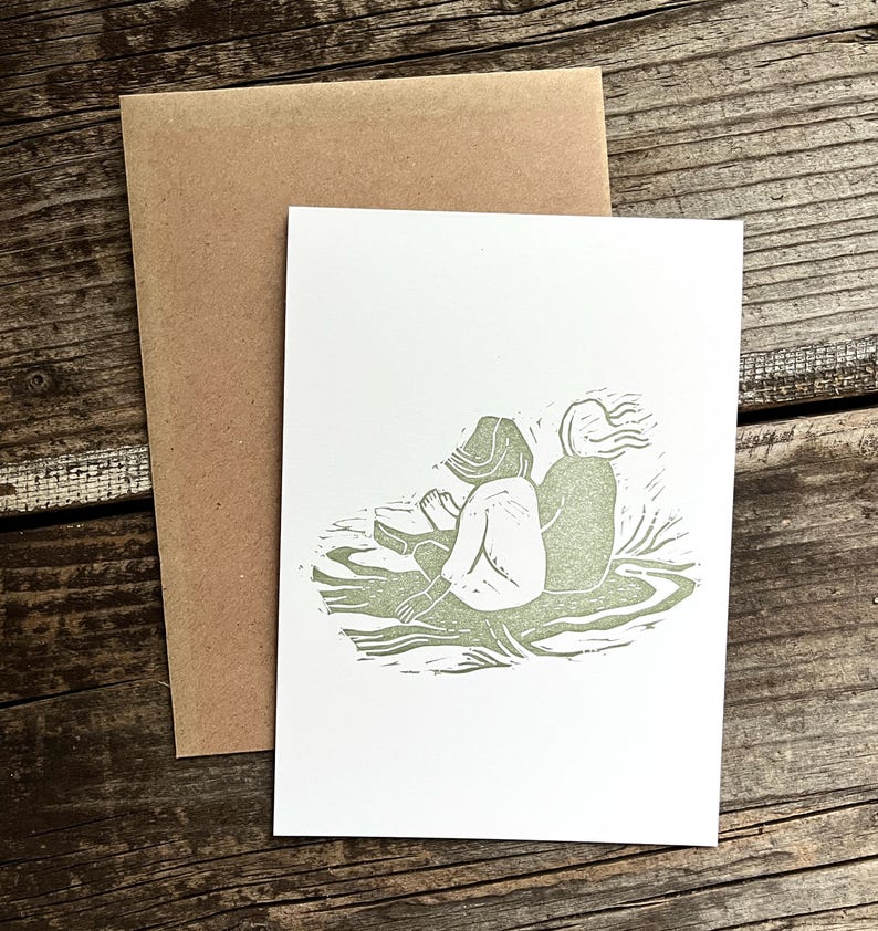 May include: A green linocut print of two people sitting back to back on a grassy surface.