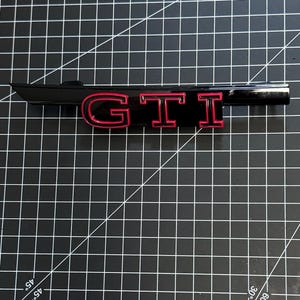 VW Golf 8 GTI grille emblem, logo. VW original part, two-tone.