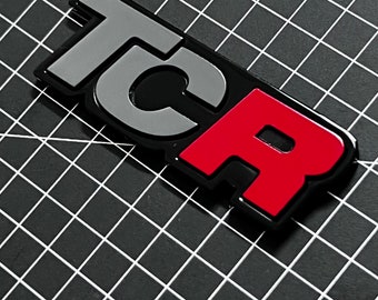 Emblemat TCR VW Golf Gti, logo na osłonie chłodnicy. Kolor: Piano Black / Pure Grey / Tornado Red