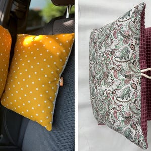 Puede incluir: Dos almohadas para reposacabezas de asiento de coche. Un par es amarillo con lunares blancos, el otro es un estampado de cachemira con un tejido de gofre burdeos. Cada almohada tiene una atadura de cord&oacute;n blanco.