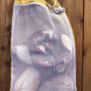 May include: A yellow and white mesh produce bag with a drawstring closure. The bag is filled with bread and pretzels.