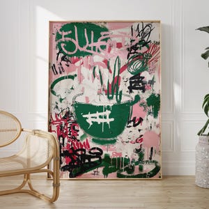 May include: Abstract art print featuring a large green bowl with a hash symbol, set against a pink and white background. The artwork includes green, red, and black graffiti-style elements, framed in a natural wood frame.