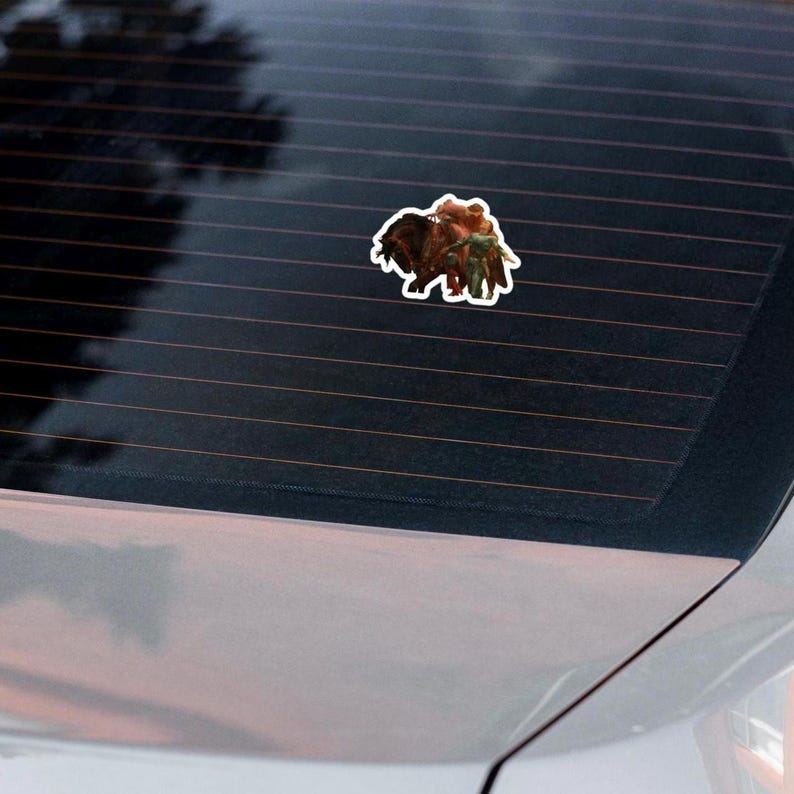 May include: A sticker featuring a detailed illustration of a bison with a person riding on its back. The sticker has a white border and is affixed to a car window. The bison is brown and the rider is wearing green and brown clothing.