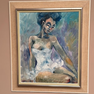 May include: Oil painting of a seated figure in a white dress, framed in a light brown burlap-textured frame. The artwork features a palette of blues, purples, and flesh tones, with visible brushstrokes. The figure is looking down, with a soft, contemplative expression.