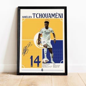 Könnte beinhalten: Ein gelbes und blaues Poster mit einem Foto eines Fußballspielers, der ein weißes Trikot mit dem Text "Emirates Fly Better" auf der Vorderseite trägt. Der Spieler trägt die Nummer 14 auf der Rückseite des Trikots. Das Poster enthält auch den Namen des Spielers "Aurélien Tchouaméni" und die Nummer 14 in großer Schrift. Das Poster enthält auch die persönlichen Daten und die Karriere des Spielers.
