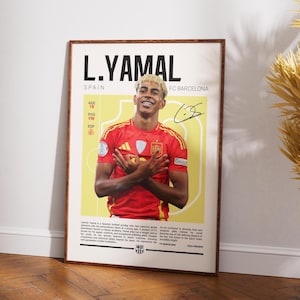Op de afbeelding: Een ingelijste poster met L. Yamal, een Spaanse voetballer, in een rood shirt. De poster bevat de naam van de speler, zijn team en een handtekening. De achtergrond is lichtgeel met tekst.