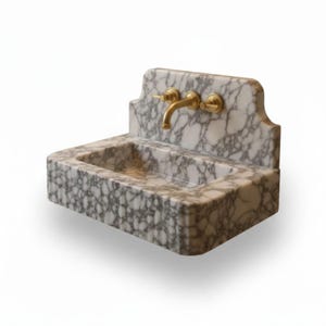 May include: A wall-mounted rectangular sink crafted from white marble with prominent grey veining. The basin features a high backsplash and is equipped with a polished brass faucet assembly consisting of a central spout and two side handles.