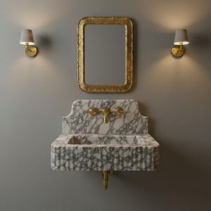 May include: A wall-mounted white and grey marble sink with a fluted front and a gold faucet. Above the sink hangs a rectangular mirror with a textured gold frame. Two gold wall sconces with white shades are positioned on either side of the mirror.