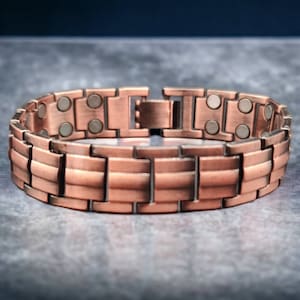 May include: A copper magnetic bracelet with a clasp closure. The bracelet is made of multiple links and has small silver magnets embedded in the links.