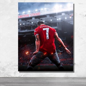 Op de afbeelding: Een voetballer draagt ​​een rood shirt met nummer 7 en de naam "RONALDO" op de rug. De speler staat op een voetbalveld met een menigte mensen op de achtergrond. Het stadion is verlicht met lichten.